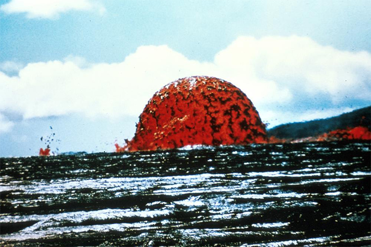 A half circle of orange lava splattered against a blue sky