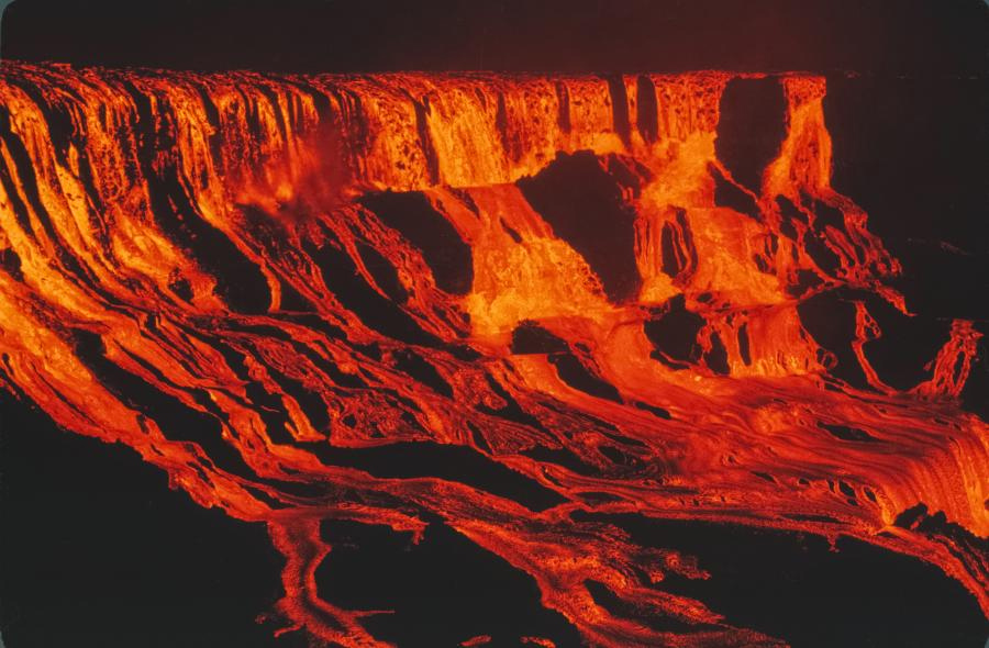 An eerie landscape of what would look exactly like a waterfall if it wasn't red and orange on a black background, made of lava