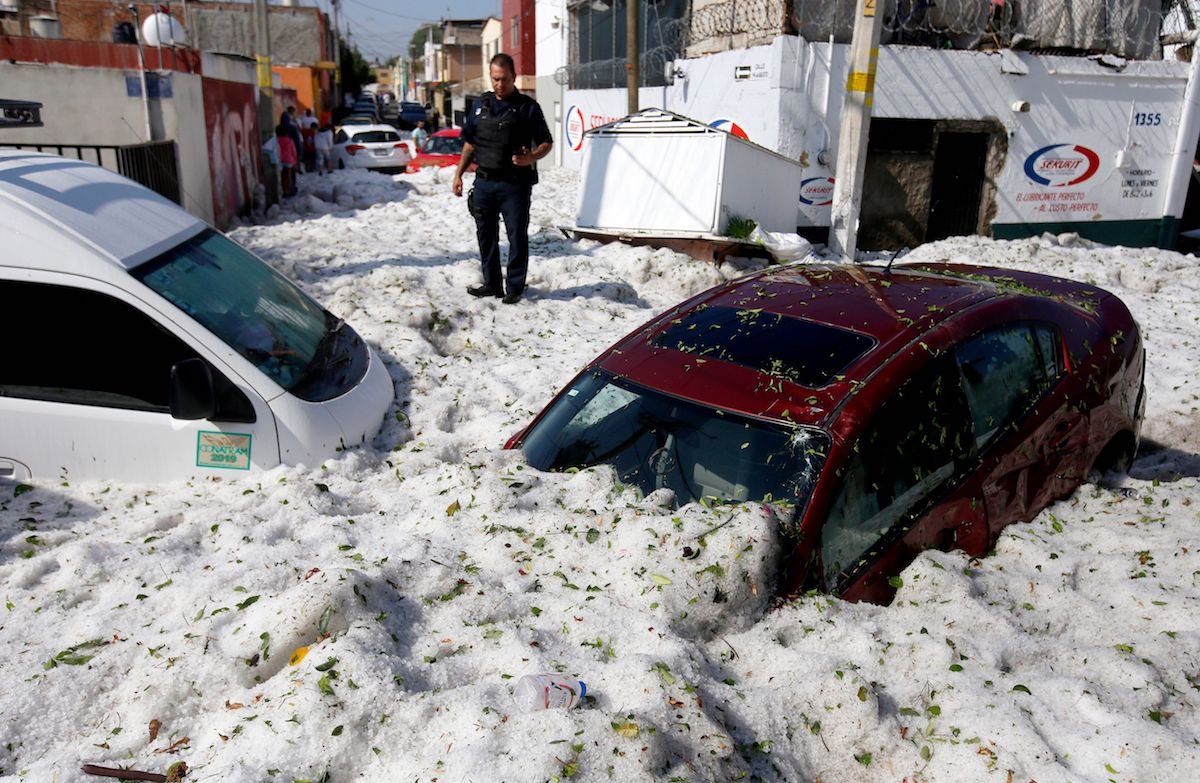 A police officer next to submerged vehicles. (Ulises Ruiz/AFP/Getty)