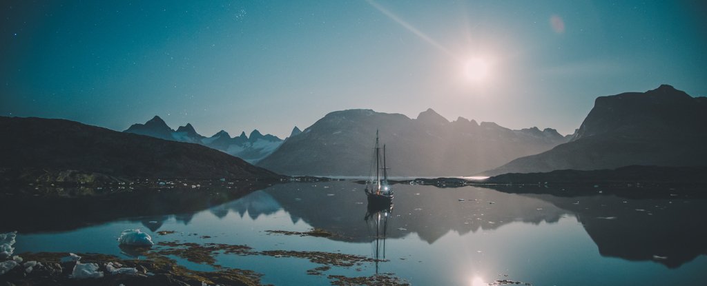 A moonlit sailboat on East Greenland’s icy fjords. 