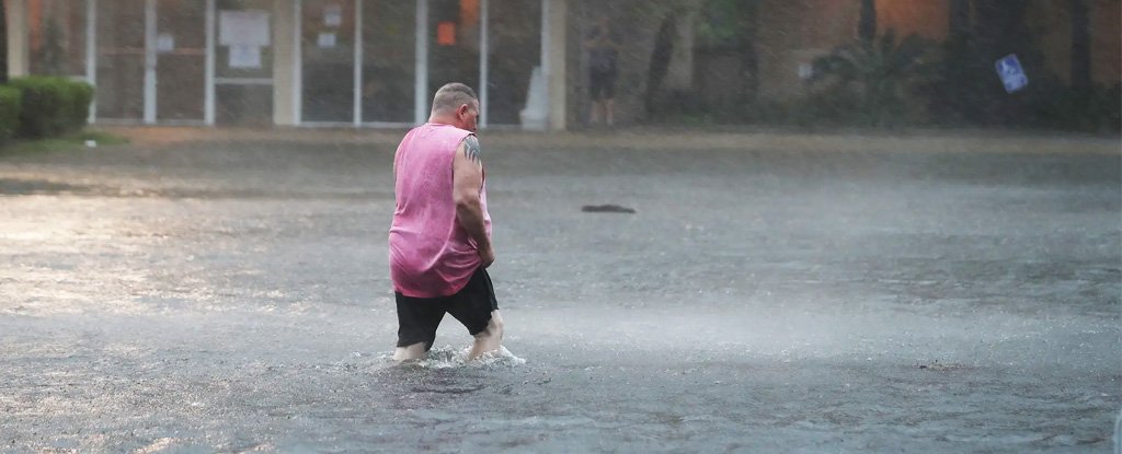 Man wades flooded parking lot in Gulf Shores, Alabama in Sept 2020. 