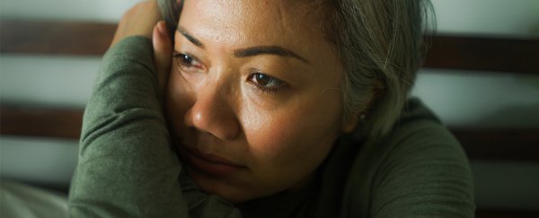 Woman looking across frame of image, hand to head, appearing tired.