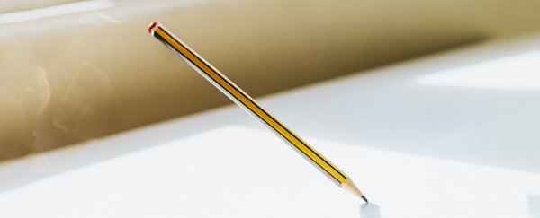A pencil balanced on its tip.