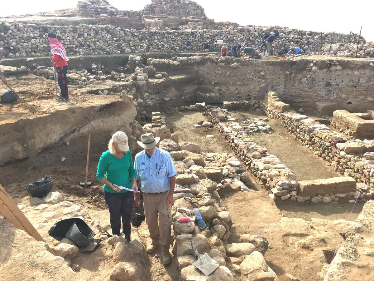 Badatelé poblíž ruin, s vrstvou destrukce zhruba v polovině každé odhalené zdi.  (Phil Sylvia, CC BY-ND)