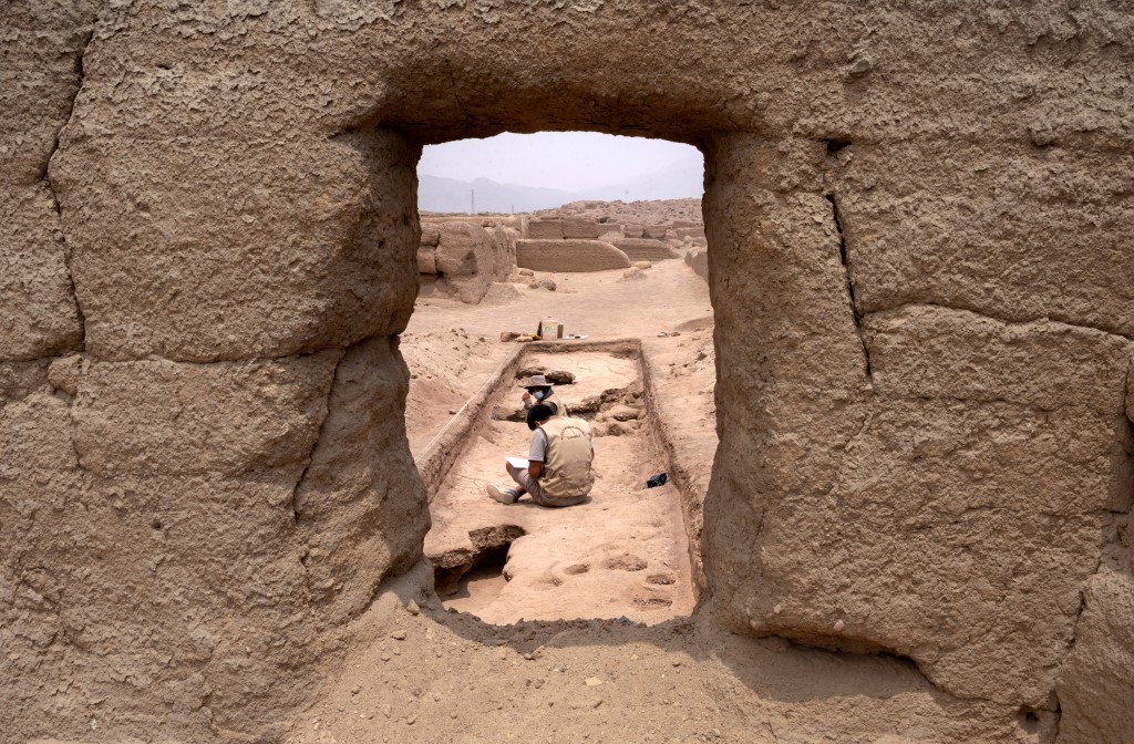 A stone archway showing a view of an archaeological dig