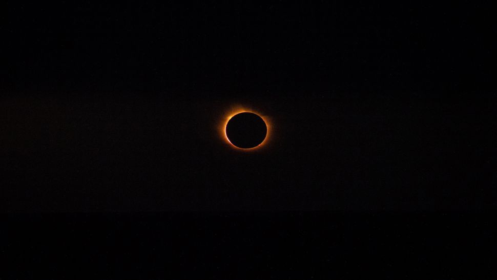 Ring of orange fire around the black sphere of the silhouetted moon.
