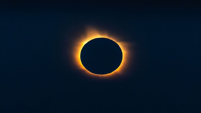 Ring of orange fire around the black sphere of the silhouetted moon.