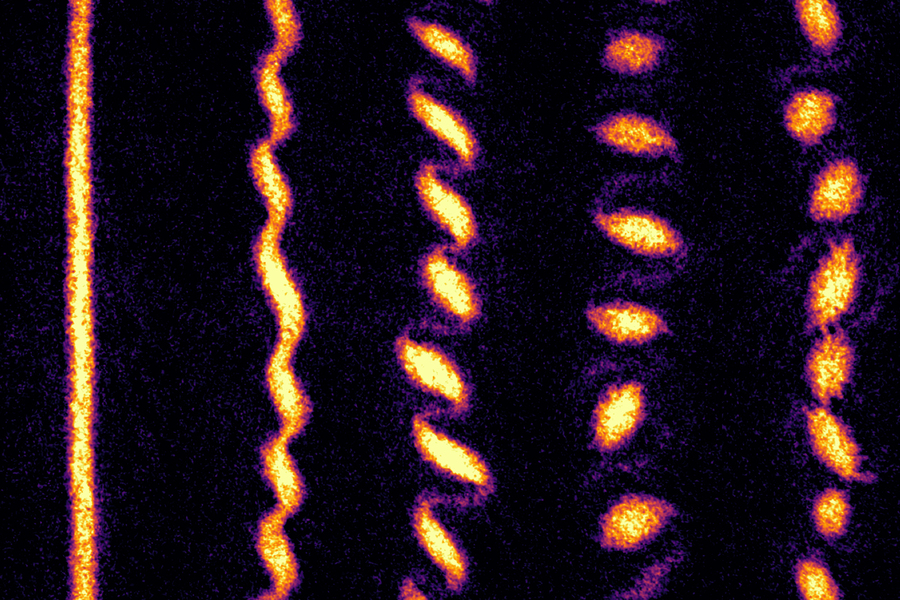 A yellow-red straight line followed by a wriggle that breaks up into a series of galaxy like swirls.