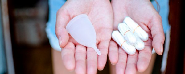 Hands holding a menstrual cup and tampons