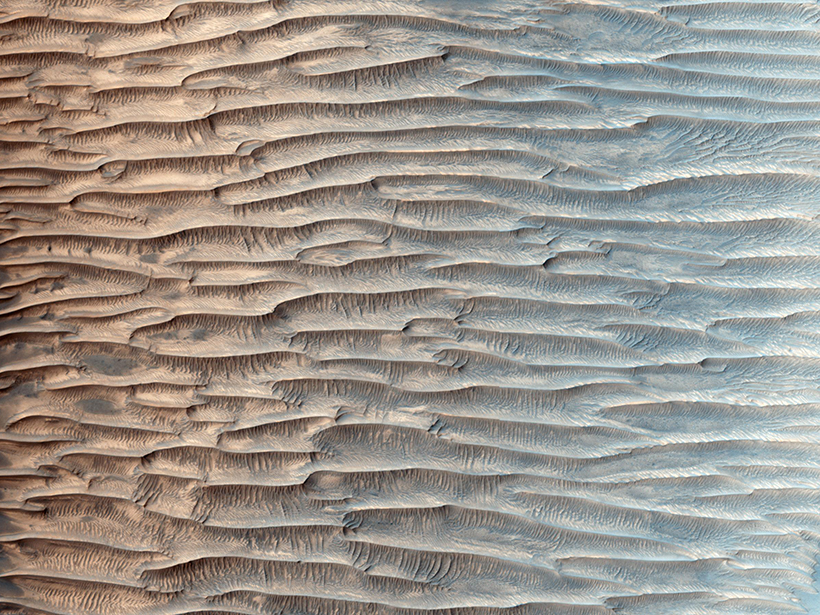 Pastel-colored image of sharp lines carved parallel across a desert surface