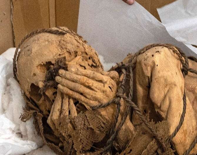 Mummy with hands bound over head.