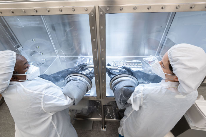 Two scientists handle a lunar tube from the Apollo 17 mission.