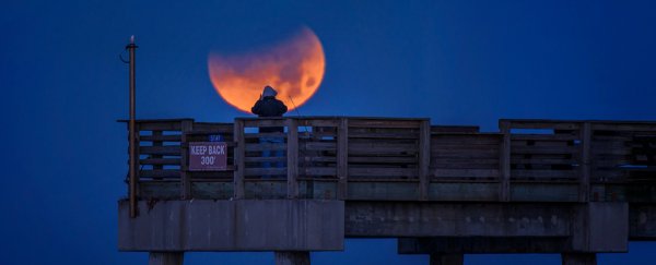There's a Total Lunar Eclipse This Weekend! Here's Your Complete Guide BloodMoonWithManOnPierInfrontOfIt_600