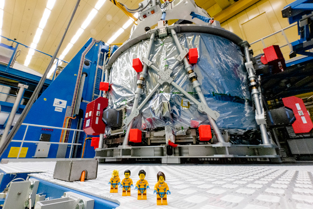 Four LEGO mini figs in front of a space capsule.