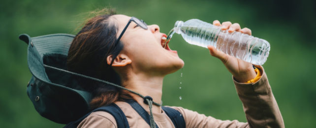 Girl wearing hat drinking from water bottle