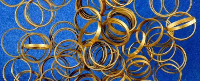 A messy pile of gold rings scattered across blue material.