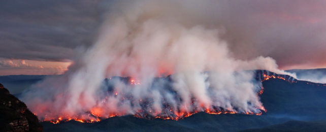 Mountain burning with huge plumes of smoke adding to the smokey sky.