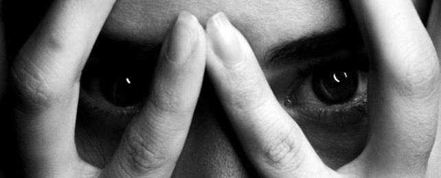 Woman looks between her fingers