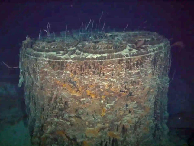 Sea life encrusted boiler from the Titanic alone on the ocean floor.