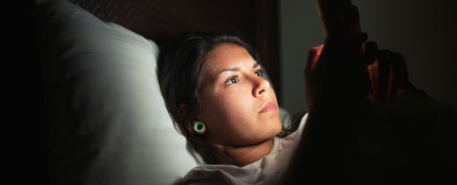 Girl with glowing phone in bed