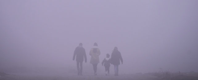 Four people walking through hazy air pollution.