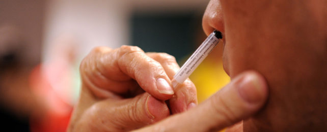 A person administers a nasal mist vaccine.