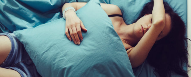 A woman in bed with a pillow over her torso.