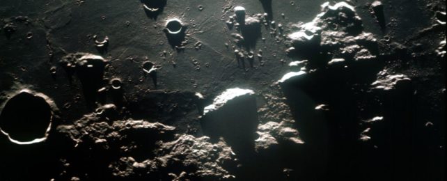 a photograph of lunar craters at the terminator, taken from orbit. Deep shadows accentuate the stark drama of the lunar landscape