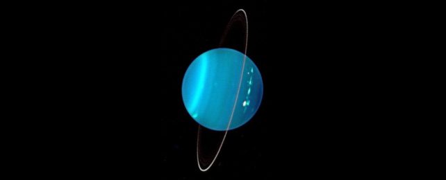 an image of uranus taken using the keck observatory. The planet appears to glow blue against the darkness, with thin, gossamer rings wrapped vertically around its middle