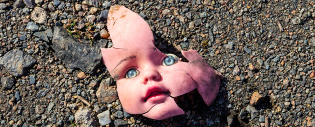 Broken plastic doll face on gravelly ground