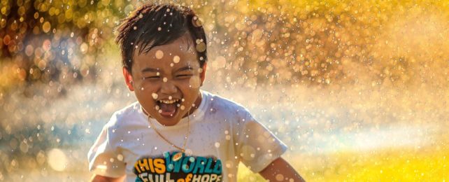Child Happily Runs Through Sprinkler