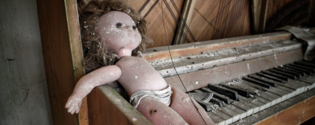 A creepy broken doll on an old broken piano.