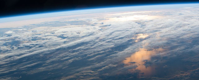 Earth as seen from space, with clouds and light swirling in the atmosphere.