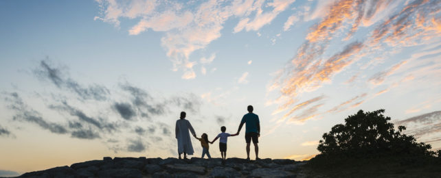 A family of four looks out at the sunrise.