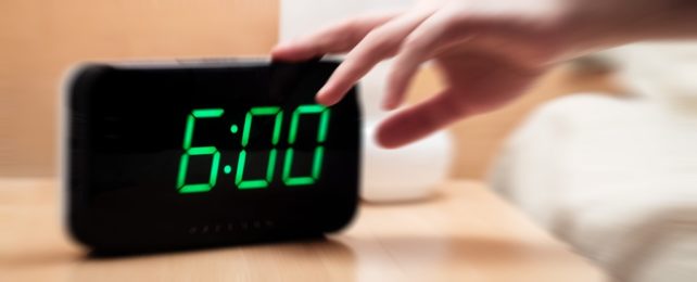 Hand Hits Snooze On Alarm Clock