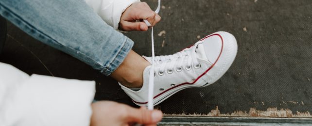 Person Laces Up White Sneakers