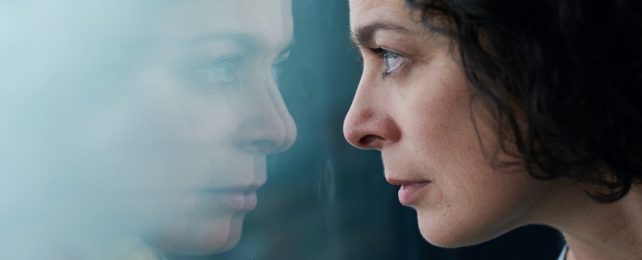 Woman Stares Through Own Reflection