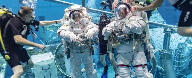 Two trainee astronauts underwater in a training pool