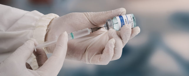 Covid vaccine bottle and a syringe being held