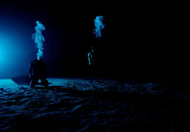 silhouettes d'astronautes au fond d'une piscine sombre