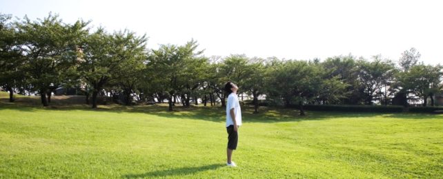 Man Looking At Sky In Green Field