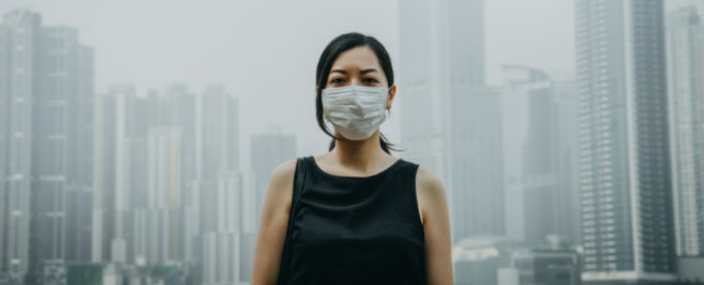 A woman wearing a mask in front of a city backdrop