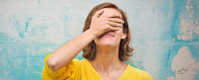 A woman covers her face with her hand.