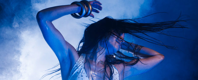 Woman dancing with arms in the air and hair flying