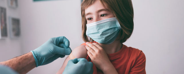 Doctor placing adhesive bandage on child's arm after vaccine