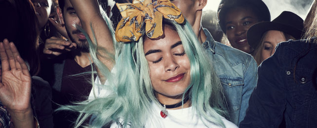 blue haired girl with eyes closed among a crowd at a concert