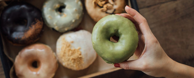 hand holding a green doughnut above a box