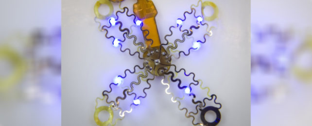A cross-shaped device with blue glowing lights