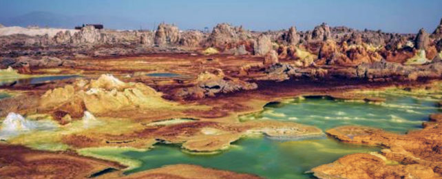 Hot barren landscape with strange rock towers and mineralized pools