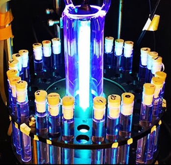 A circle of test tubes containing water, irradiated by a cylindrical UV light bulb.